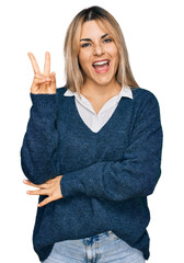 Young caucasian woman wearing casual clothes smiling with happy face winking at the camera doing victory sign with fingers. number two.