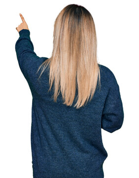 Young caucasian woman wearing casual clothes posing backwards pointing ahead with finger hand