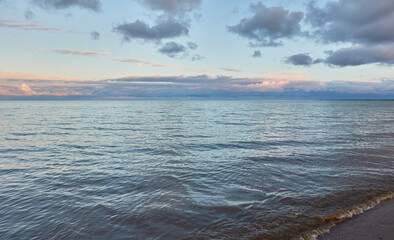Baltic sea shore (beach) at sunset, panoramic view. Soft sunlight, midnight sun, clear sky, glowing clouds. Saaremaa island, Estonia. Atmospheric summer landscape