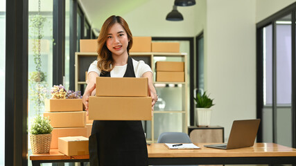 Fototapeta na wymiar Young woman entrepreneur working in home office, preparing parcel boxes of product for delivery. Online selling, e-commerce concept
