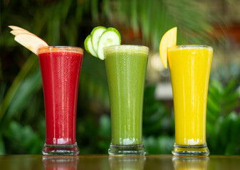 mixed organic fresh fruit juices in cafe with.garden background