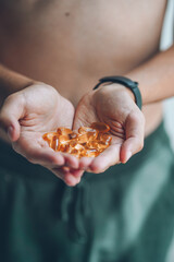 Obraz premium A handful of vitamins in the hands of a young guy. Bright Omega-3 capsules. Medicinal product of animal origin. Fish oil source of vitamins A and D