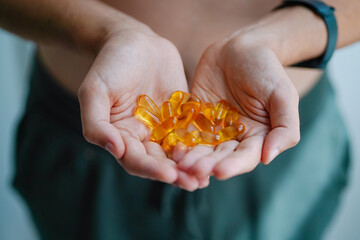 A handful of vitamins in the hands of a young man. Bright Omega-3 capsules. Medicinal product of animal origin. Fish oil source of vitamins A and D