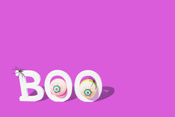 Word Boo. Halloween banner background with eyes and spiders on purple background. Lettering, poster, card design concept.