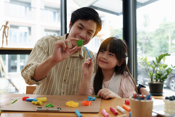 Adorable little girl and father playing with colorful plasticine. Handmade skills training