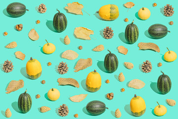 Creative autumn idea with pumpkins and leaves on greenish turquoise background. Aesthetic Thanksgiving or Halloween composition in a minimalist style, trendy colors.
