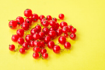 Sprigs of red currant on yellow background. Fresh bright currant. Sweet juicy currant, organic berries harvest - healthy eating and food concept.