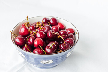 Bowl of fresh red cherries on white background. Sweet cherries in the bowl on white background closeup. Cherry organic berries harvest - healthy eating and food concept