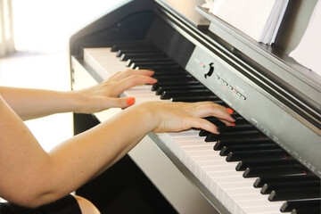 female hands play a melody on white and black piano keys