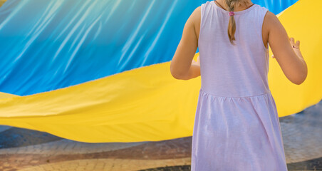 Niña pequeña irreconocible, sujetando la bandera de Ucrania. Fotografía horizontal con espacio para texto. - obrazy, fototapety, plakaty