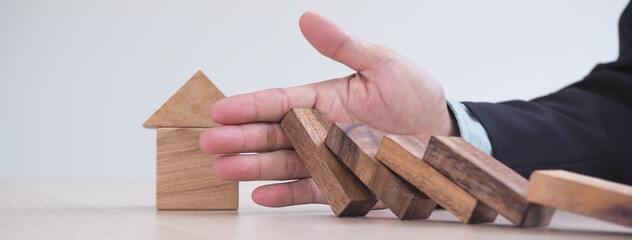 Protection finance from domino effect concept. Hands stop domino effect before destroy home.