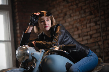 Fototapeta na wymiar Young beautiful girl in the black leather jacket and sunglasses is posing near the motorbike concept.