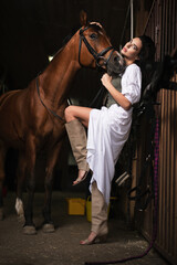 Young beautiful girl with the horse in the stable.