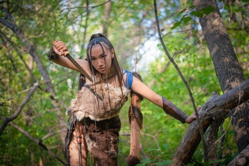 Beautiful asian woman with the dagger is hunting in the forest concept.