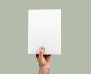Hand holding closed book mockup with white cover. Novel, encyclopedia, code, Bible template. Reading hobby, study, learning new information concept