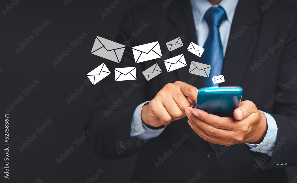 Poster businessman in a suit using a smartphone with an email icon while standing on a gray background