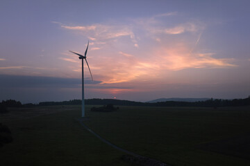 Obraz premium Aerial, scenic view of wind power plant silhouette against colorfull sunset sky. Drone inspection of wind-powered electrical generator.