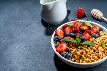 Healthy breakfast granola with fresh berry - strawberry, raspberry, blueberry on black background