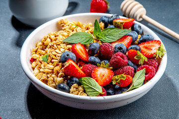 Healthy breakfast granola with fresh berry - strawberry, raspberry, blueberry on black background