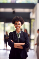 Portrait Of Businesswoman Standing In Lobby Of Busy Modern Office Building