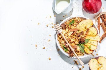Healthy autumn breakfast granola. Apple pie granola with muesli, cinnamon spices, apples slices, honey and nuts, on white stone background copy space