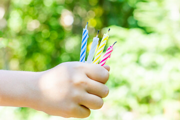Extinguished candles in a child's hand. Colored birthday candles. End of the party. After party.