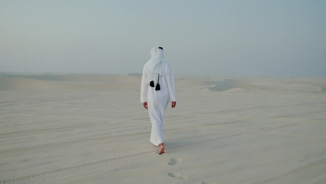 men with qatari traditional outfit walking in the desert of Qatar
