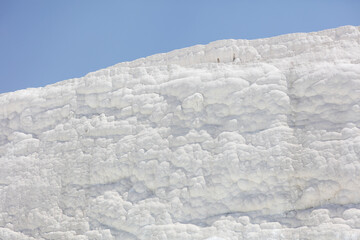 A mountain of white volcanic limestone rock against a blue sky.