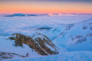 Evening light lay on a winter mountain valley covered with low clouds