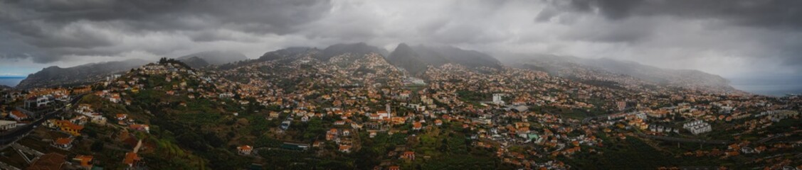 Fototapeta na wymiar Aerial panoramic view of Funchal city from Miradouro Pico dos Barcelos. Madeira, Portugal. Foggy and rainy weather. October 2021