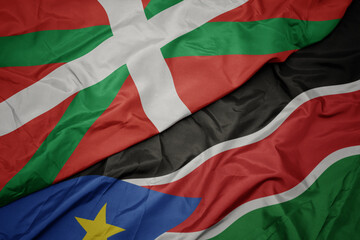 waving colorful flag of south sudan and national flag of basque country.