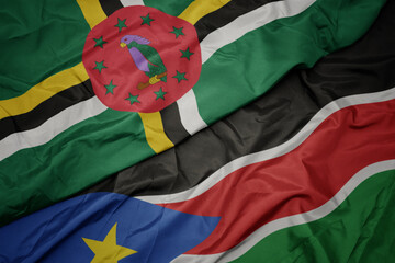waving colorful flag of south sudan and national flag of dominica.
