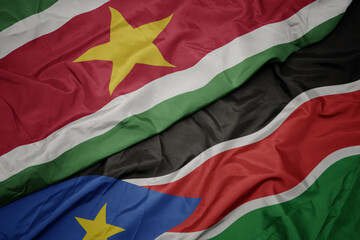 waving colorful flag of south sudan and national flag of suriname.