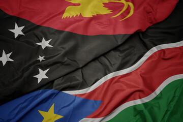 waving colorful flag of south sudan and national flag of Papua New Guinea