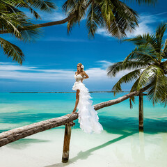Bride on the beach. Stylish female model in elegant long gown dress on the Maldives beach....