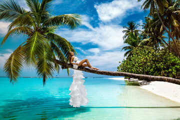 Bride on the beach. Stylish female model in elegant long gown dress on the Maldives beach....