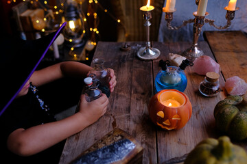 pumpkins, candles, little female witch prepares witch's potion, magic items on the table, funny...