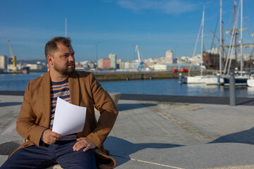 A business man sits in the port with documents.