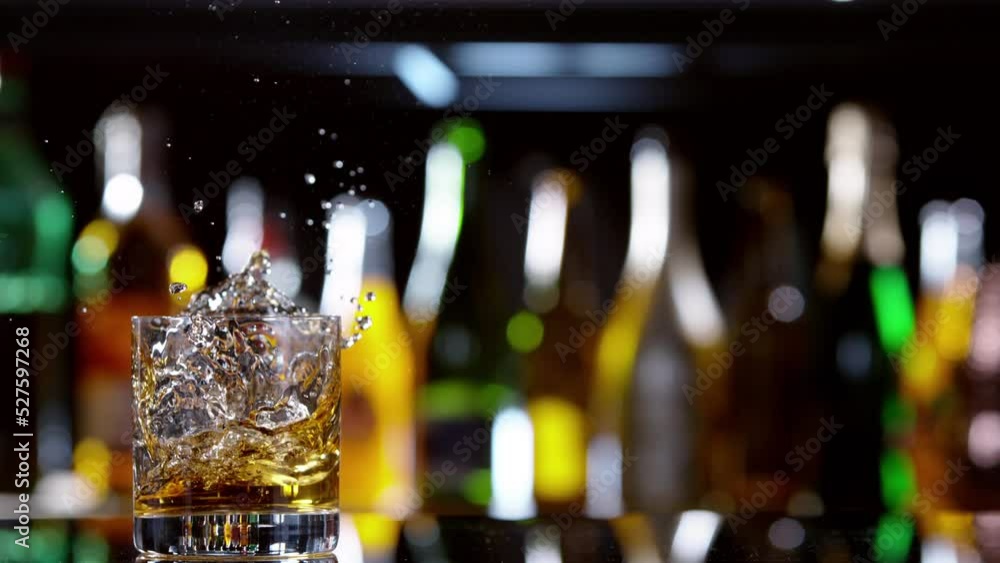 Poster super slow motion of falling ice cube into whiskey drink, camera motion. speed ramp effect. filmed o