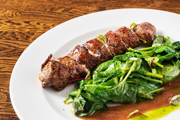 beef with roasted spinach on the wooden background