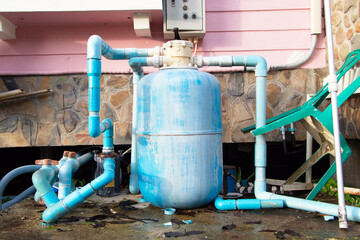 Small water pump plastic with PVC pipe blue and motor broken old  next to side home. Electric...