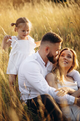 Mother with father hugging with their daughter in the field