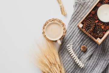 Flat lay knitted plaid, cup of coffee, wheat, autumn decor on white background. Still life nordic, Scandinavian home fall desk table.