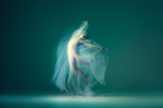 Graceful ballet dancer dancing with white cloth, fabric isolated on green background. Art, motion, action, flexibility, inspiration concept.