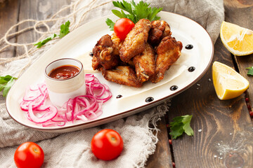 Fried chicken wings and legs in a plate on a wooden table.