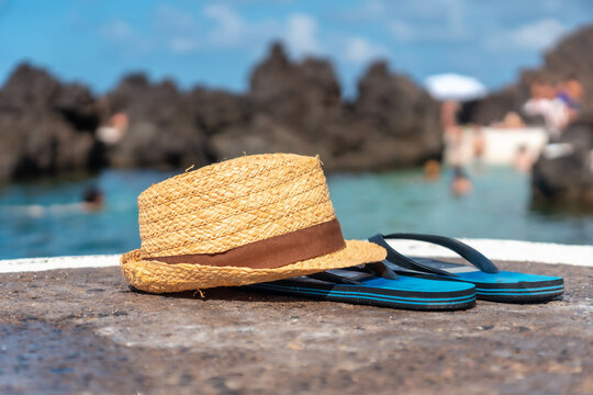 Hat and flip flops next to a natural pool, coastal town of Porto Moniz, Madeira