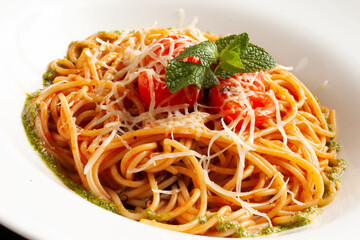 Pasta with minced meat, tomatoes and cheese in a plate. On a dark background.