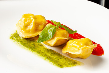 Ravioli with sauce in a bowl. On a dark background.
