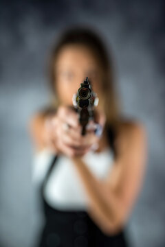 beautiful brunette sexy woman with a gun in her hand directed it at the victim.