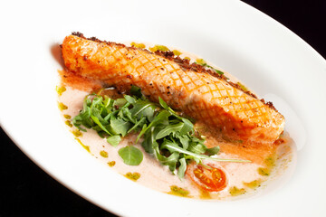 Grilled salmon steak in a bowl. On a dark background.